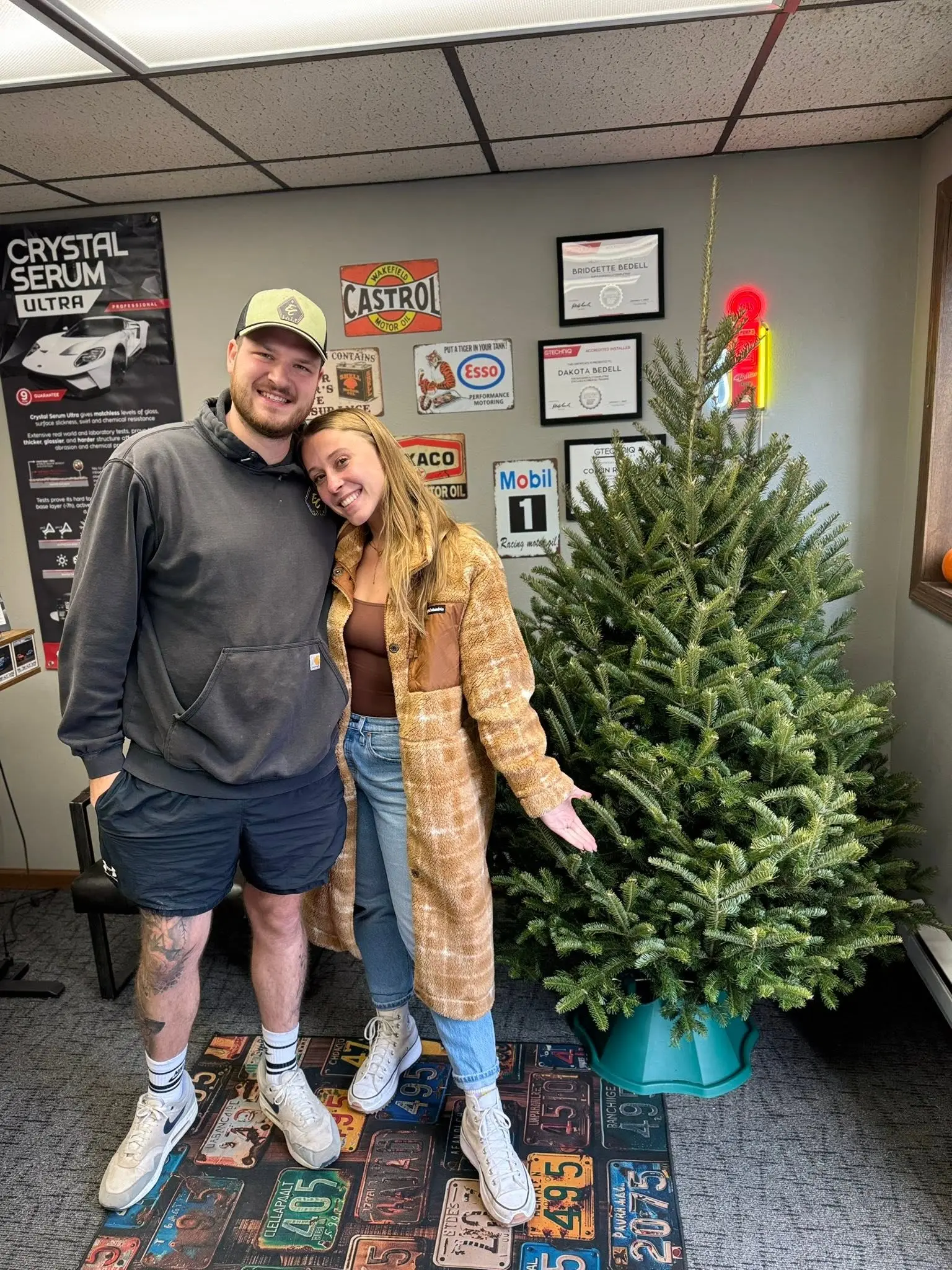 Customers standing with a fresh Christmas tree delivered to their office