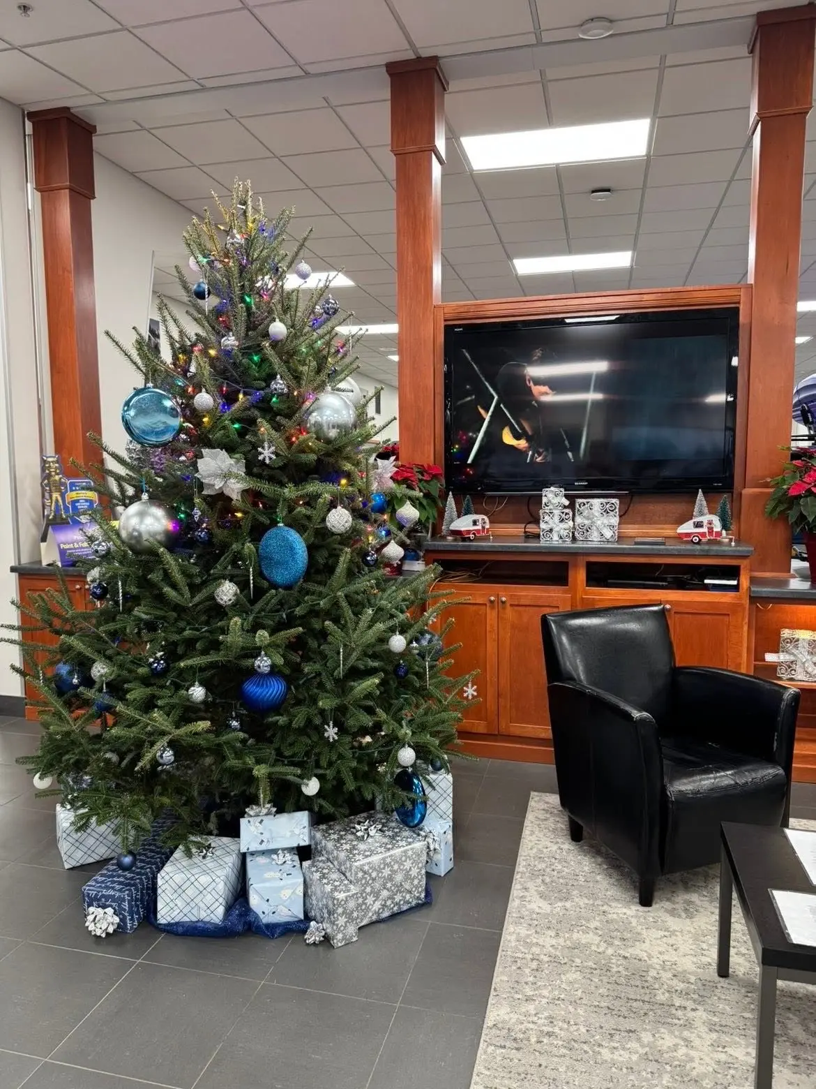 Decorated Christmas tree with blue ornaments and gifts in a business lobby